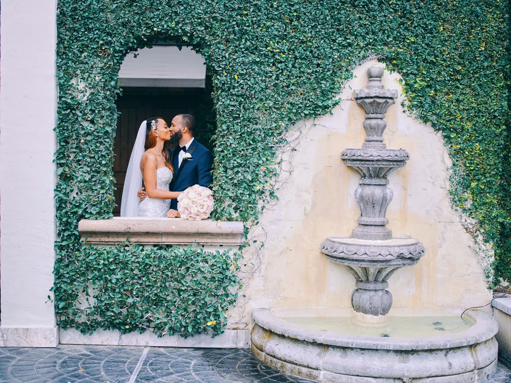 Bride and groom kissing at the courtyard fountain window at The Bell Tower on 34th, Houston, TX.