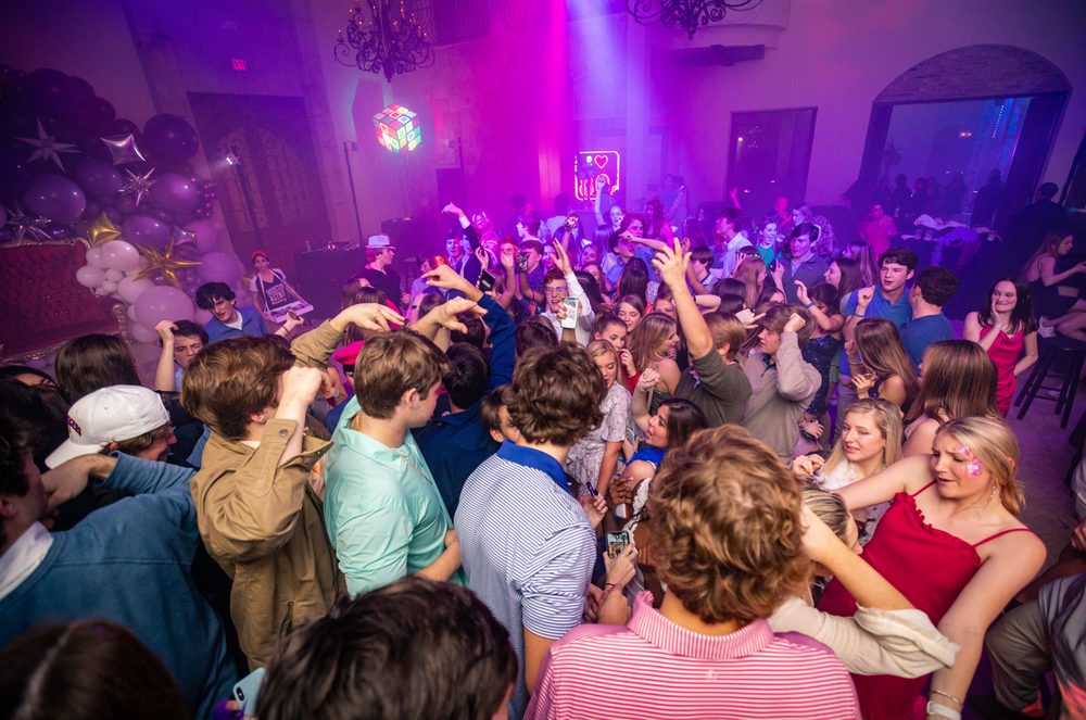 Packed dance floor under magenta spotlights at a prom at The Bell Tower on 34th, Houston, TX.