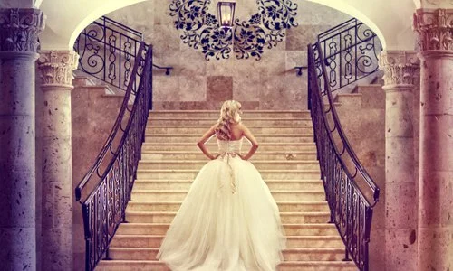 Bride on the grand staircase under the chandelier at The Bell Tower on 34th, Houston, TX.